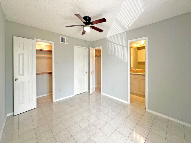unfurnished bedroom with baseboards, visible vents, connected bathroom, ceiling fan, and a textured ceiling
