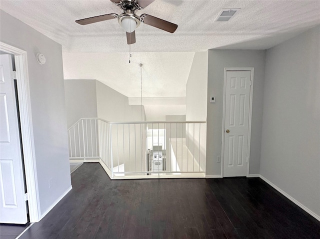 spare room with dark wood-style floors, baseboards, visible vents, and a textured ceiling
