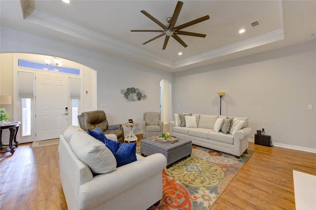 living area with arched walkways, a tray ceiling, and visible vents