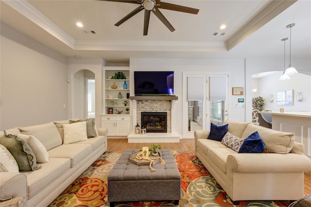 living area with light wood-type flooring, arched walkways, visible vents, and ornamental molding