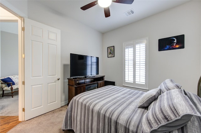 bedroom featuring ceiling fan, visible vents, and light colored carpet