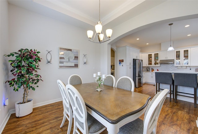 dining space with baseboards, arched walkways, dark wood-style flooring, an inviting chandelier, and recessed lighting