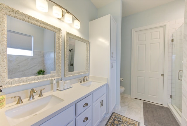 bathroom with double vanity, a stall shower, a sink, and toilet