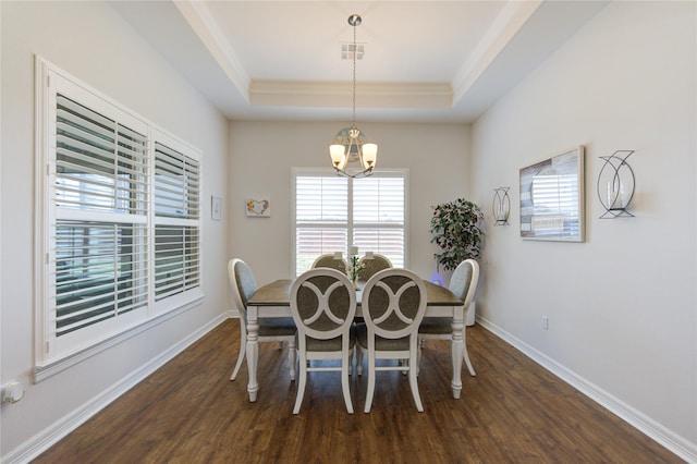 dining room featuring dark wood-type flooring, a tray ceiling, visible vents, and baseboards