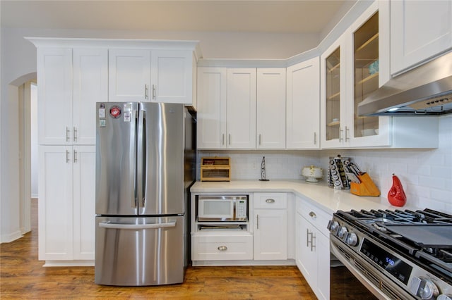 kitchen featuring arched walkways, light countertops, appliances with stainless steel finishes, and white cabinetry