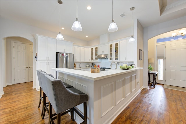 kitchen featuring white cabinets, glass insert cabinets, decorative light fixtures, freestanding refrigerator, and light countertops