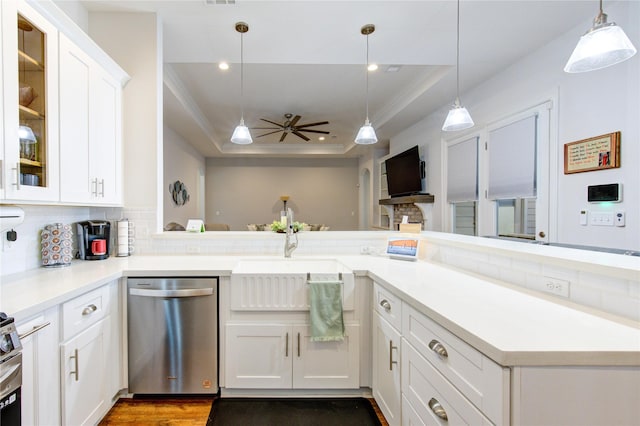 kitchen featuring dishwasher, light countertops, a raised ceiling, and glass insert cabinets