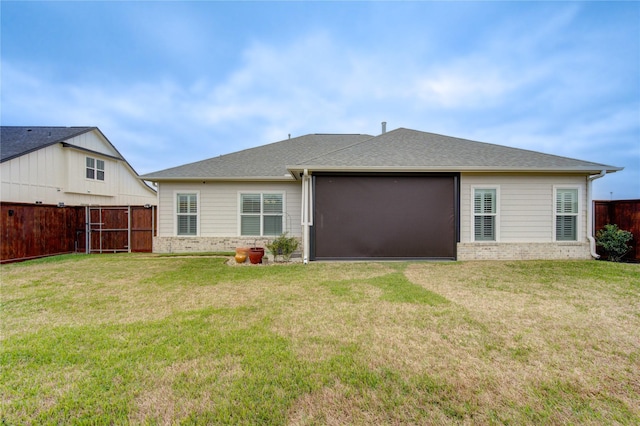 back of property featuring a yard, brick siding, fence, and a shingled roof