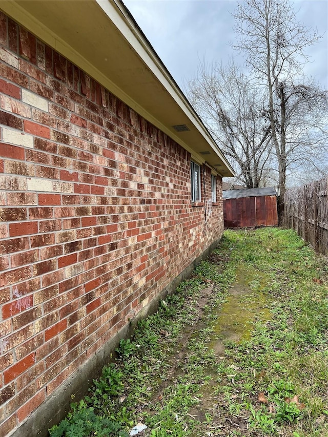 view of home's exterior with brick siding and fence