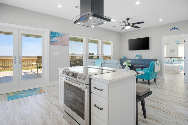 12971/2 Mabry St, Gilchrist, TX 77617 - kitchen with electric range, open floor plan, white cabinets, island range hood, and a kitchen breakfast bar