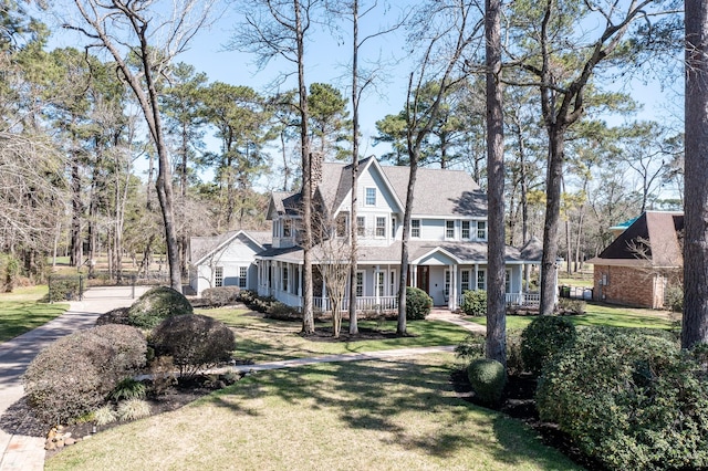 exterior space featuring covered porch, a chimney, and a front yard