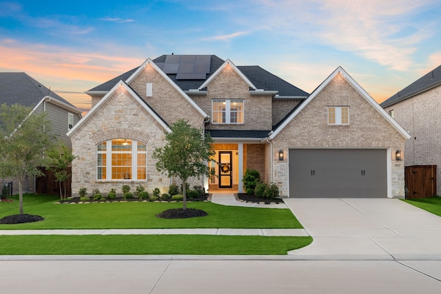 traditional-style home featuring solar panels, brick siding, fence, concrete driveway, and a front lawn