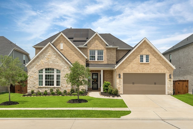 view of front of house with brick siding, a front yard, roof mounted solar panels, fence, and driveway