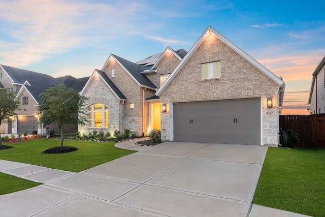 view of front facade featuring brick siding, fence, concrete driveway, stone siding, and a lawn