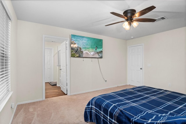 carpeted bedroom featuring ceiling fan, visible vents, and baseboards