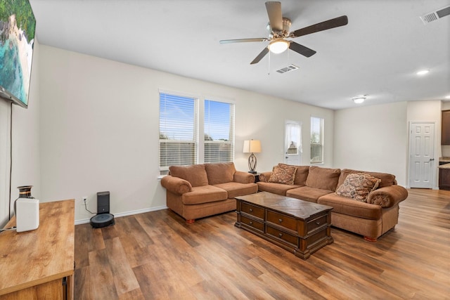 living area with ceiling fan, wood finished floors, visible vents, and baseboards