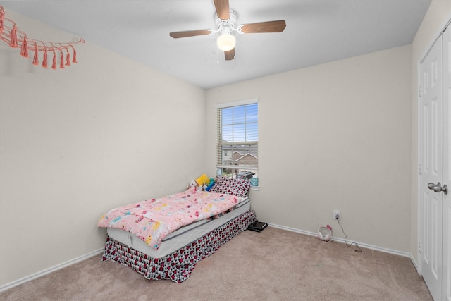 bedroom featuring light carpet, ceiling fan, a closet, and baseboards