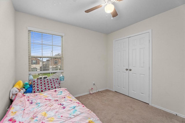 bedroom with light carpet, a closet, a ceiling fan, and baseboards