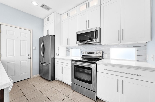 kitchen with stainless steel appliances, decorative backsplash, visible vents, and white cabinetry