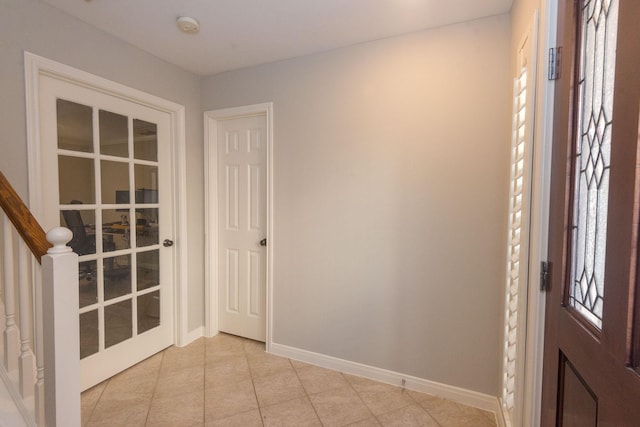 foyer featuring light tile patterned floors, stairs, and baseboards