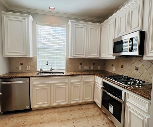 kitchen featuring white cabinets, dark stone counters, stainless steel appliances, and a sink