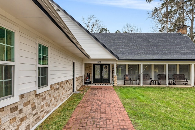 entrance to property with a shingled roof, stone siding, french doors, a lawn, and a chimney