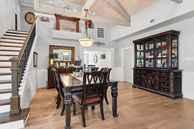 dining space with visible vents, stairway, light wood-style flooring, wooden ceiling, and beamed ceiling