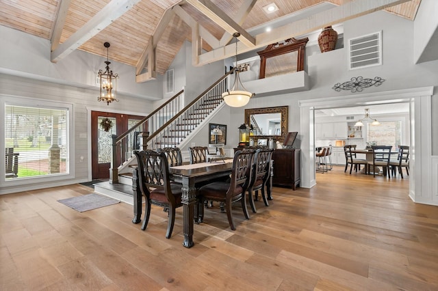 dining space featuring visible vents, light wood-style flooring, wood ceiling, a chandelier, and stairs