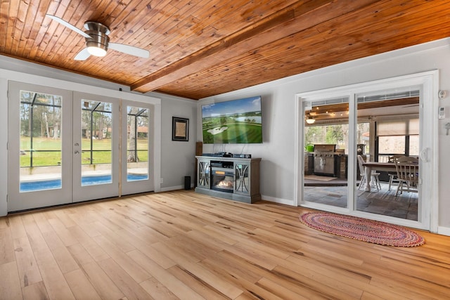 unfurnished living room with a fireplace, light wood finished floors, a ceiling fan, wooden ceiling, and baseboards