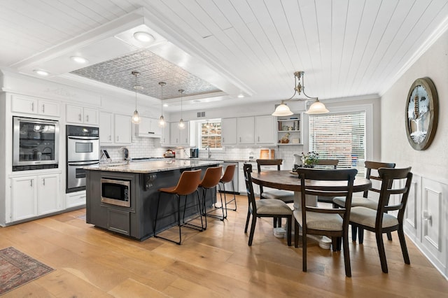 kitchen featuring hanging light fixtures, stainless steel appliances, white cabinetry, and a center island