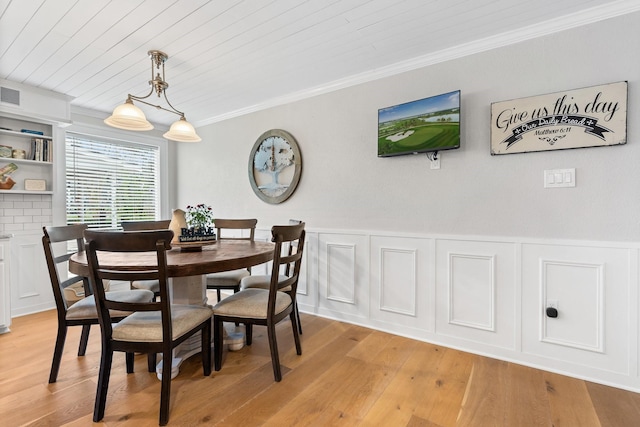 dining room with visible vents, a wainscoted wall, wood ceiling, ornamental molding, and light wood-type flooring