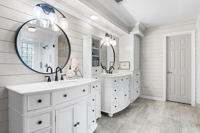 bathroom featuring crown molding, two vanities, a sink, and wood walls