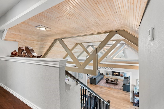 hallway with vaulted ceiling with beams, wooden ceiling, wood finished floors, and baseboards