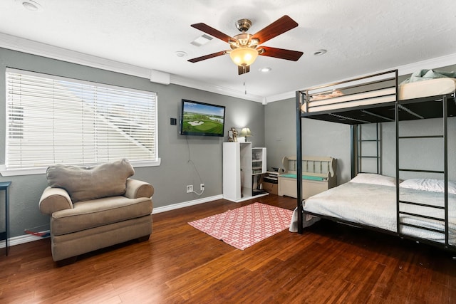 bedroom with crown molding, ceiling fan, dark wood-type flooring, and baseboards