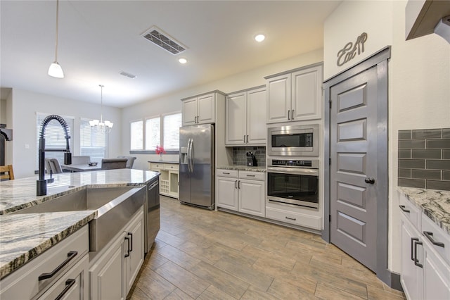 kitchen featuring stainless steel appliances, visible vents, decorative light fixtures, and white cabinetry