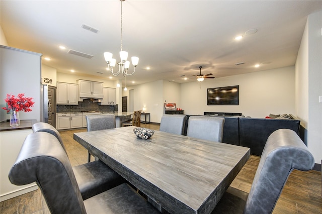 dining space featuring ceiling fan with notable chandelier, light wood finished floors, visible vents, and recessed lighting