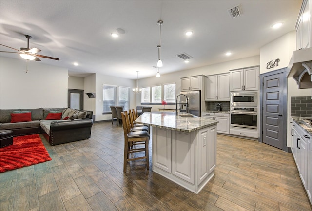 kitchen featuring an island with sink, visible vents, appliances with stainless steel finishes, and pendant lighting