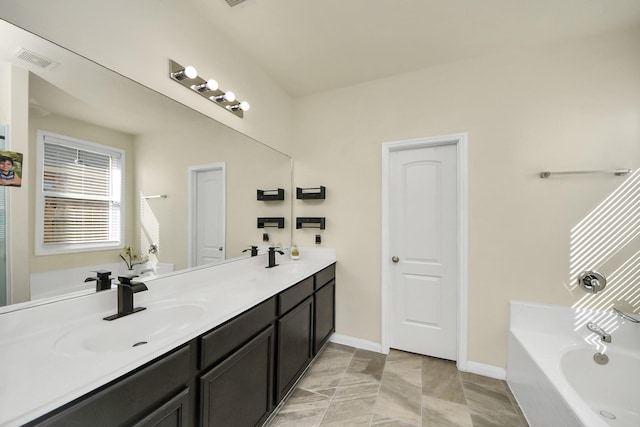 bathroom with a sink, visible vents, baseboards, a bath, and double vanity