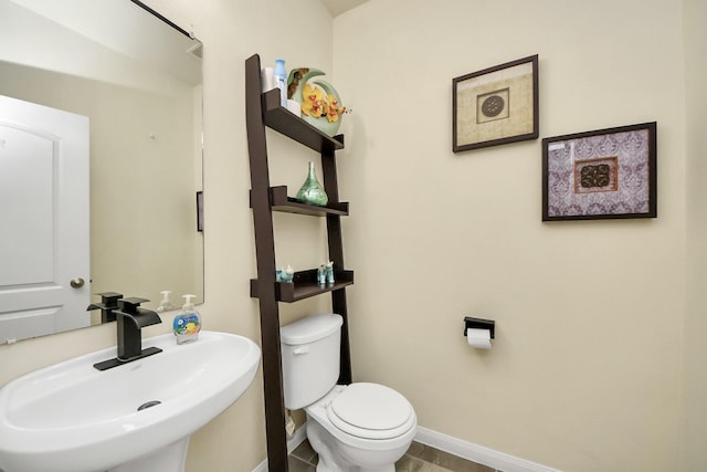 bathroom featuring toilet, baseboards, and a sink