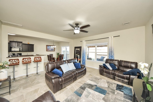 living area featuring ceiling fan, visible vents, and baseboards