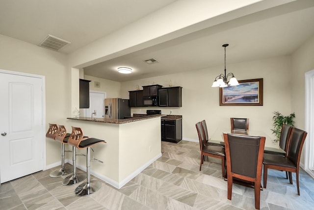 kitchen with visible vents, stainless steel fridge with ice dispenser, a peninsula, an inviting chandelier, and black microwave