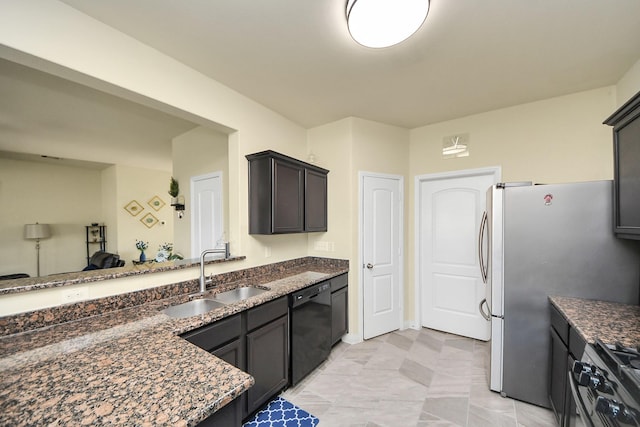 kitchen with dark brown cabinetry, black dishwasher, dark stone countertops, a sink, and stainless steel range with gas stovetop