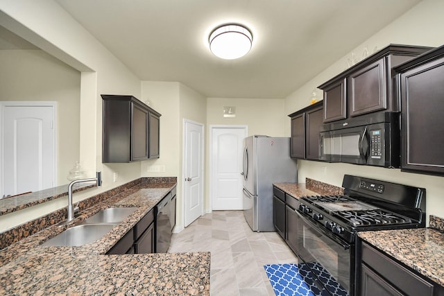 kitchen with dark stone counters, black appliances, dark brown cabinets, and a sink