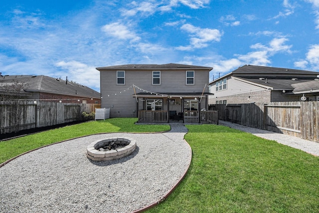 rear view of house with a patio area, a fenced backyard, a fire pit, and a lawn