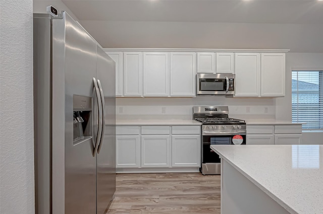 kitchen featuring stainless steel appliances, white cabinets, light wood finished floors, and light stone countertops