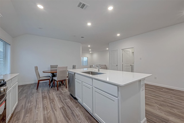 kitchen featuring a sink, light wood-style floors, light countertops, stainless steel dishwasher, and a center island with sink