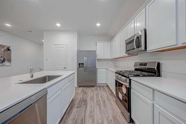 kitchen with appliances with stainless steel finishes, white cabinets, light countertops, and a sink