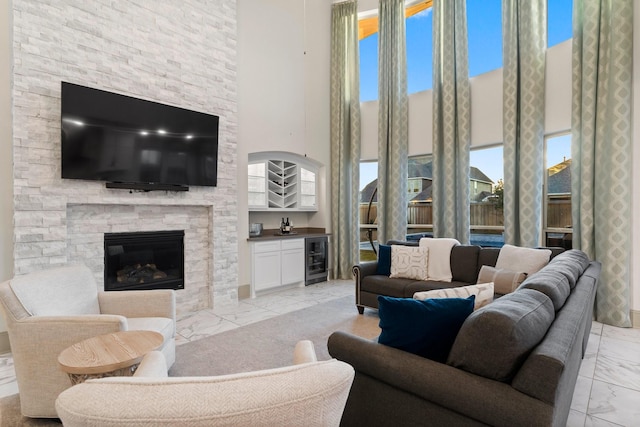 living room with wine cooler, marble finish floor, a fireplace, and wet bar