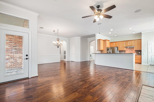 unfurnished living room with ceiling fan with notable chandelier, crown molding, arched walkways, and wood finished floors