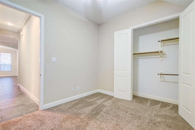 unfurnished bedroom featuring attic access, baseboards, a closet, and light colored carpet